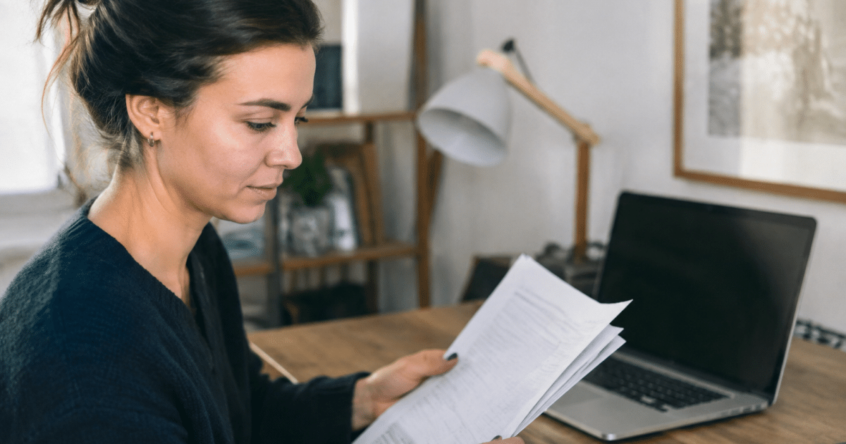 Personne tenant documents pret bancaire devant ordinateur bureau