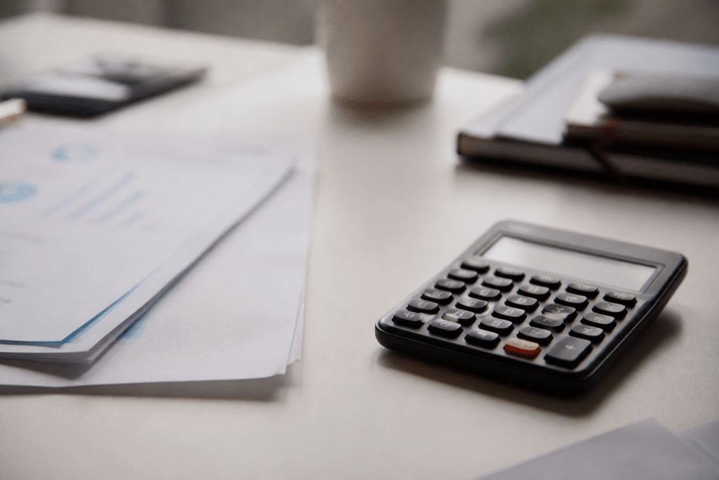 Documents financiers et calculatrice sur bureau blanc