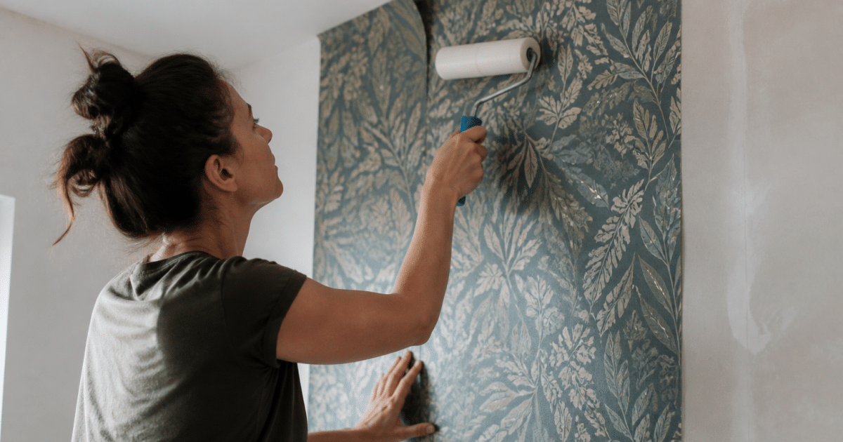 Personne appliquant papier peint sur mur avec rouleau