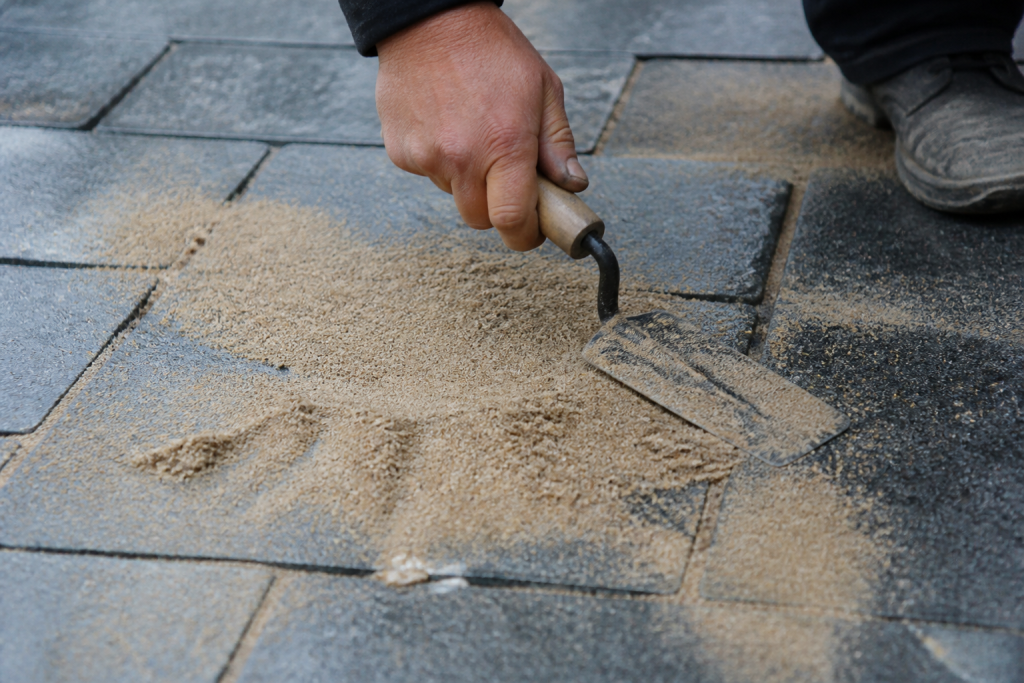 Sable remplit espaces entre paves gris humides