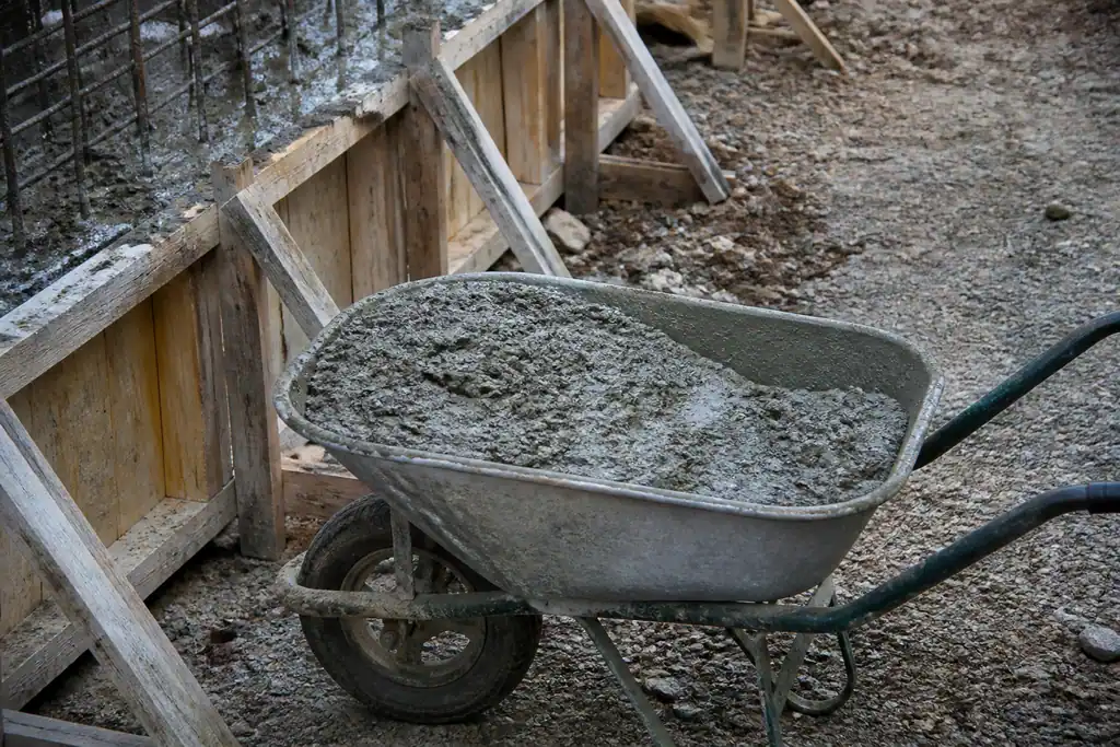 Brouette de beton frais devant un coffrage en bois