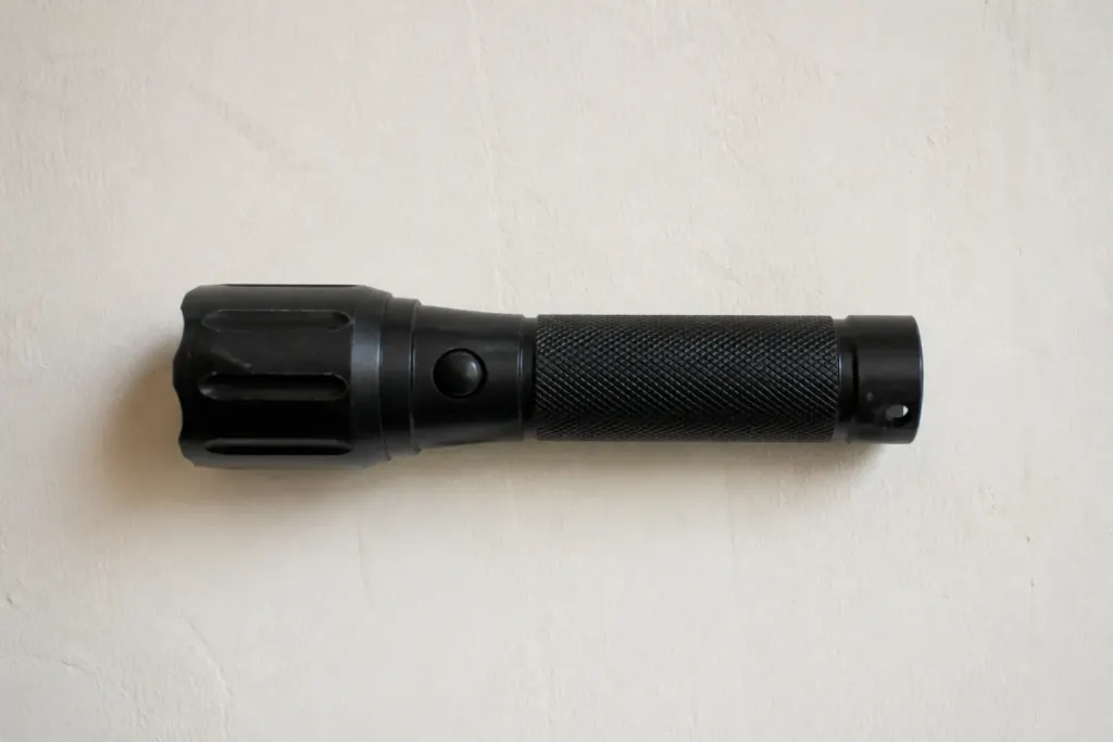 Lampe torche posee a plat sur un mur blanc